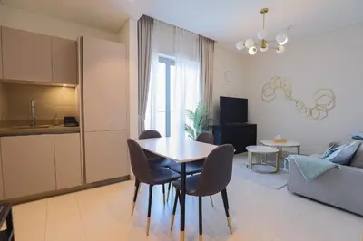 a kitchen and a living room with a table and chairs at Cosy 1BR in Sobha Hartland in Dubai
