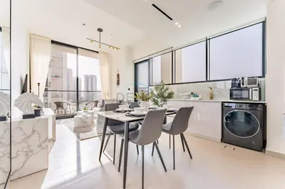 a kitchen and dining room with a table and chairs at Minutes from Circle Mall, Grocery Stores & Bus Stop 2BR with Mini Private Pool on Balcony, Binghatti Tulip, Jumeirah Village Circle by Deluxe Holiday Homes in Dubai