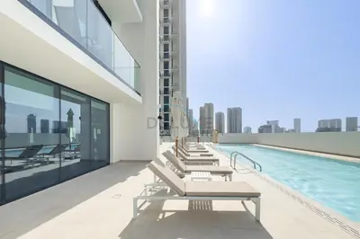 a row of lounge chairs on a building with a pool at Minutes from Circle Mall, Grocery Stores & Bus Stop 2BR with Mini Private Pool on Balcony, Binghatti Tulip, Jumeirah Village Circle by Deluxe Holiday Homes in Dubai