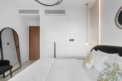 a bedroom with a white bed and a mirror at Novity Signature Homes in Dubai
