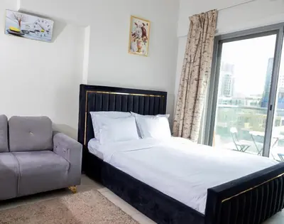 a bedroom with a bed and a chair and a window at Stunning Studio Apartment in Jvc in Dubai