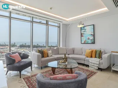 a living room with a couch and a table and chairs at HiGuests - Oceanfront Luxurious 3BR at Th8 Palm Dubai in Dubai