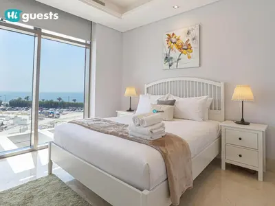 a bedroom with a white bed with a large window at HiGuests - Oceanfront Luxurious 3BR at Th8 Palm Dubai in Dubai