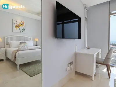 a bedroom with a bed and a desk and a tv at HiGuests - Oceanfront Luxurious 3BR at Th8 Palm Dubai in Dubai