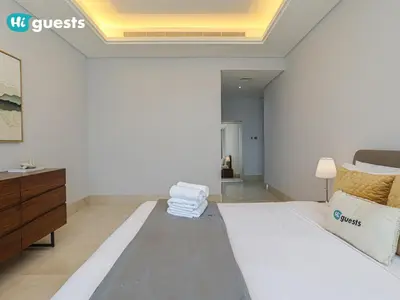 a white bedroom with a bed and a dresser at HiGuests - Oceanfront Luxurious 3BR at Th8 Palm Dubai in Dubai