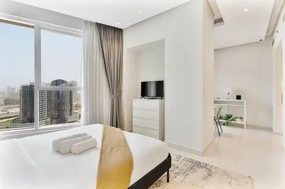 a white bedroom with a large bed and a large window at Elegant Studio in Business Bay near Burj Khalifa in Dubai