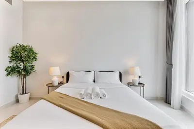 a bedroom with a white bed with two white slippers at Elegant Studio in Business Bay near Burj Khalifa in Dubai