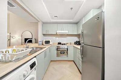 a kitchen with white cabinets and a stainless steel refrigerator at Stylish 1BR in Dubai Marina with Balcony, Pool & Walk to Beach in Dubai