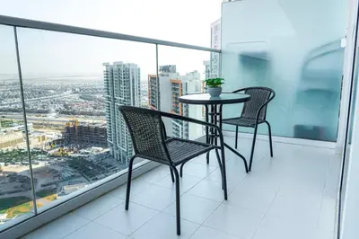 two chairs and a table on a balcony with a view at BirdsEye Cozy Studio Mesmerizing Golf Views in Dubai