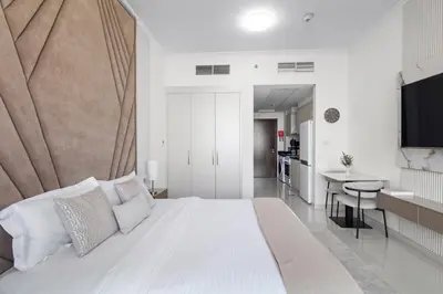a white bedroom with a large bed and a kitchen at BirdsEye Cozy Studio Mesmerizing Golf Views in Dubai