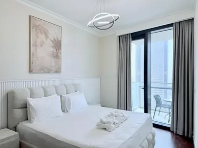 a white bedroom with a large bed and a window at Charming 1 BR with Balcony Retreat in Dubai