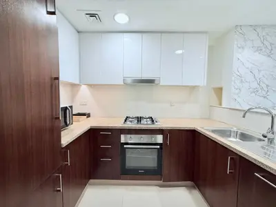 a kitchen with white cabinets and a stove top oven at Charming 1 BR with Balcony Retreat in Dubai