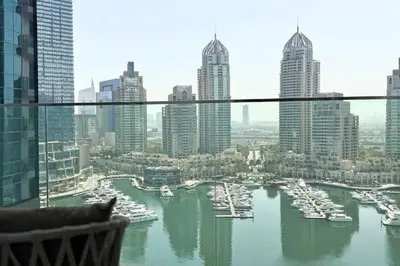a cat sitting in a chair looking out a window at a harbor at Luxury 1-Bedroom Apartment with Full Marina View in Dubai