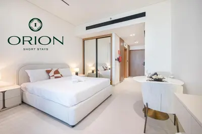 a white bedroom with a bed and a table at Stunning Luxury Studio with Jacuzzi and Canal View on High Floor, Close to Dubai Mall, Swimming Pool, Advanced Gym with PT, Sauna, Steam Room, Ice Bath, Swimming Pool, Best Building in Area in Dubai