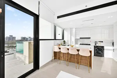 a kitchen with white cabinets and a bar with stools at Golden Stays - Private Pool in Binghatti Gardenia I Coastal Charm I Luxe 2BR Escape in Dubai