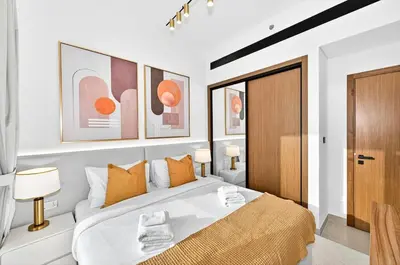 a bedroom with a large white bed with orange pillows at Golden Stays - Private Pool in Binghatti Gardenia I Coastal Charm I Luxe 2BR Escape in Dubai