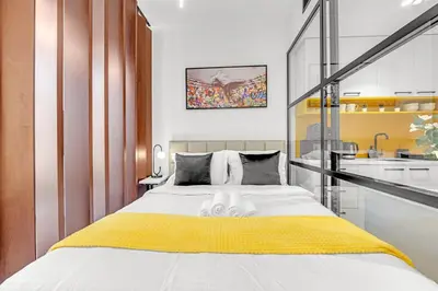 a bedroom with a large bed with a yellow blanket at Waves - Cozy & Modern JVC Escape With Pool & Gym Access in Dubai