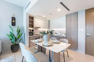 a kitchen and dining room with a table and chairs at Panoramic High-Floor 1BR Overlooking Yachts and Dubai Water Canal, Moments from JBR Beach, LIV MarinaMarine Transport, and Skydive Dubai, LIV Marina, Dubai Marina by Deluxe Holiday Homes in Dubai