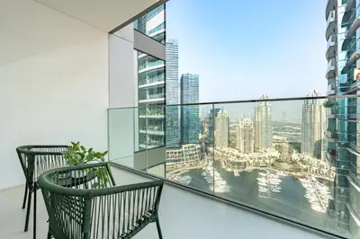 a balcony with two chairs and a view of the city at Panoramic High-Floor 1BR Overlooking Yachts and Dubai Water Canal, Moments from JBR Beach, LIV MarinaMarine Transport, and Skydive Dubai, LIV Marina, Dubai Marina by Deluxe Holiday Homes in Dubai