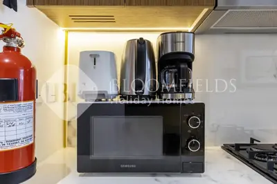 a kitchen with a coffee maker on top of a microwave at Bloomfeilds Comfortable STU Azizi Rivera in Dubai