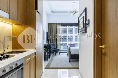 a kitchen with a sink and a living room at Bloomfeilds Comfortable STU Azizi Rivera in Dubai