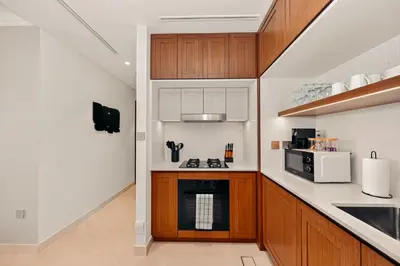 a kitchen with wooden cabinets and a stove top oven at Luxury 2BR Retreat Gorgeous Beach & Skyline Views in Dubai