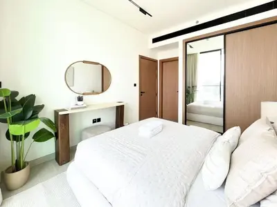 a white bedroom with a large bed and a mirror at Serene Palette 1BR in Binghatti Azure with Gym & Pool in Dubai