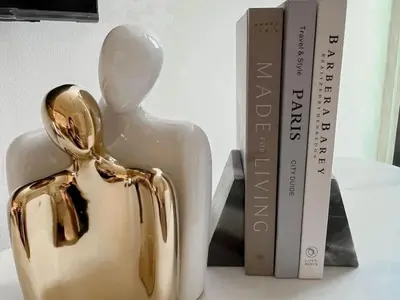 a statue of a person next to a book at Serene Palette 1BR in Binghatti Azure with Gym & Pool in Dubai