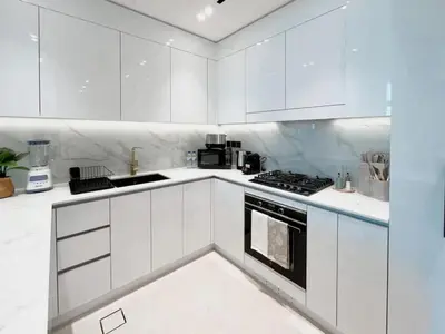 a white kitchen with white cabinets and a stove at Serene Palette 1BR in Binghatti Azure with Gym & Pool in Dubai