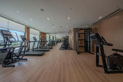 a gym with a row of treadmills and machines at Serene Palette 1BR in Binghatti Azure with Gym & Pool in Dubai