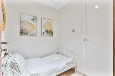 a white room with a bed and two pictures on the wall at Radiant - 3BR - JVC - near Sports City & Autodrome in Dubai