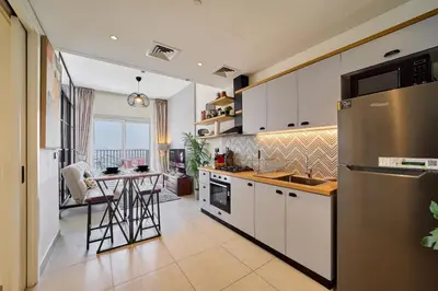 a kitchen with white cabinets and a table in it at 1BR in Collective With Pool, Gym and CoWorking Space in Dubai