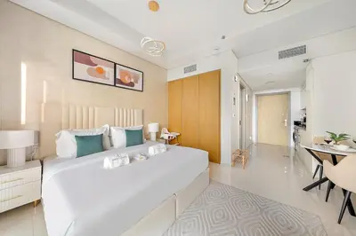 a bedroom with a large white bed and a table at Chic Studio in Dubai with Pool View Retreat Near Business Bay & Jumeirah Beach in Dubai
