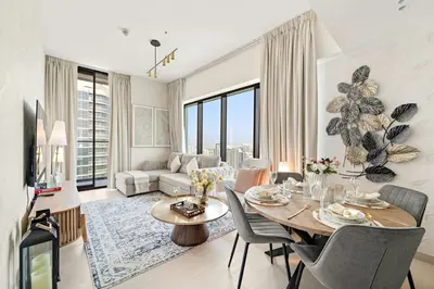 a living room with a table and a couch at Stylish 2BR JVC with Pool, Gym Access, and City Skyline Views in Dubai