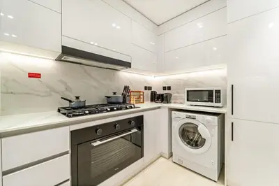 a kitchen with a washing machine and a microwave at Stylish 2BR JVC with Pool, Gym Access, and City Skyline Views in Dubai