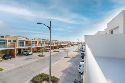 a street with cars parked in a parking lot at EasyGo Spacious 3BR with Garden in DAMAC Hills 2 in ‘Ūd al Bayḑāʼ