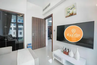 a bedroom with a large tv on a wall at EasyGo Spacious 3BR with Garden in DAMAC Hills 2 in ‘Ūd al Bayḑāʼ