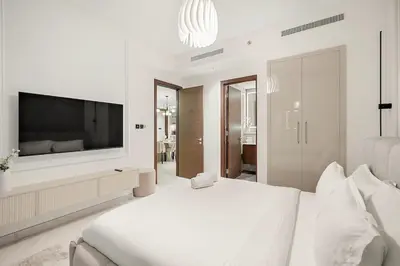 a white bedroom with a large bed and a flat screen tv at FIRST CLASS 4BR Sobha Skyline Luxury in Dubai