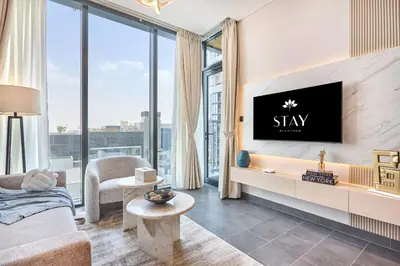 a living room with a tv on a wall at STAY BY LATINEM Luxury 1BR Holiday Home CB 0902 Near Burj Khalifa in Dubai