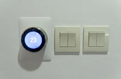 a digital clock on a wall next to two light switches at Scent of the Palms by Lagom in Dubai