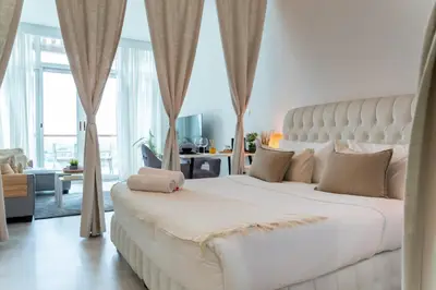 a bedroom with a large white bed with a large window at Scent of the Palms by Lagom in Dubai