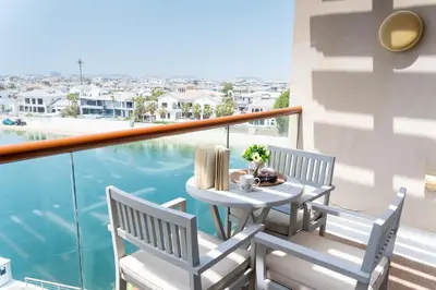 a table and chairs on a balcony with a view of the water at Scent of the Palms by Lagom in Dubai
