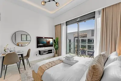 a white bedroom with a large bed and a table at Chic Dubai Retreat at Azizi Riviera 65 in Dubai