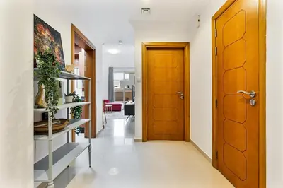 a hallway with a wooden door and white walls at Retro 1BR APT in Marina Near JBR Beach & Mall in Dubai