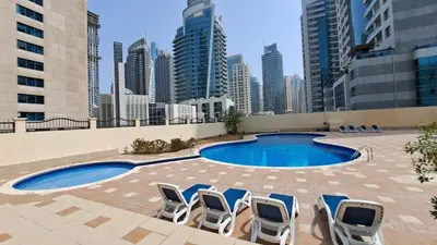 a swimming pool with chairs and a building at DRUVYA HOLIDAY HOMES, Marina Diamond 1, Close to Sobha Realty Metro 3 min walkable in Dubai