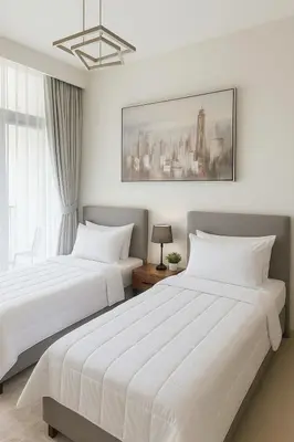 two white beds in a bedroom with a picture on the wall at Cosy 2BR Business Bay with Canal view and Swimming pool in Dubai