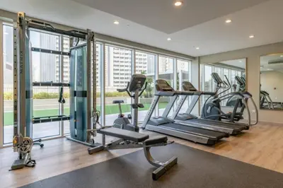 a gym with treadmills and ellipticals in a building at Cosy 2BR Business Bay with Canal view and Swimming pool in Dubai