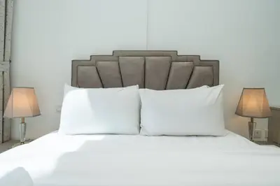 a white bed with white pillows and two lamps at Luxury JVC 1BR plus Maids Room Escape with Terrace in Dubai