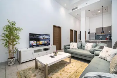 a living room with a couch and a tv at Luxury JVC 1BR plus Maids Room Escape with Terrace in Dubai