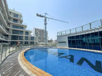 a swimming pool in front of a building with a crane at Elegant 2BR Apartment Private Pool by Czechin in Dubai